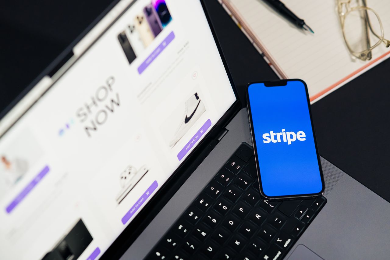 about-us-02 Mobile phone displaying Stripe app on a laptop with an eCommerce site open, symbolizing online shopping.